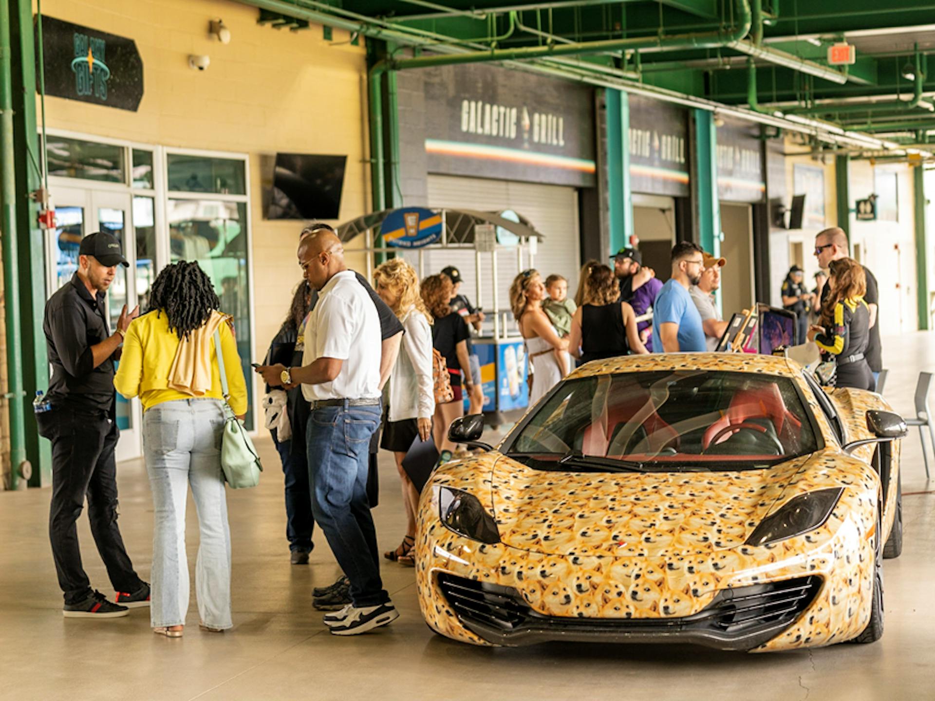 Dogepalooza crowd and the Dogeclaren (A McClaren covered in Dogecoin pictures)