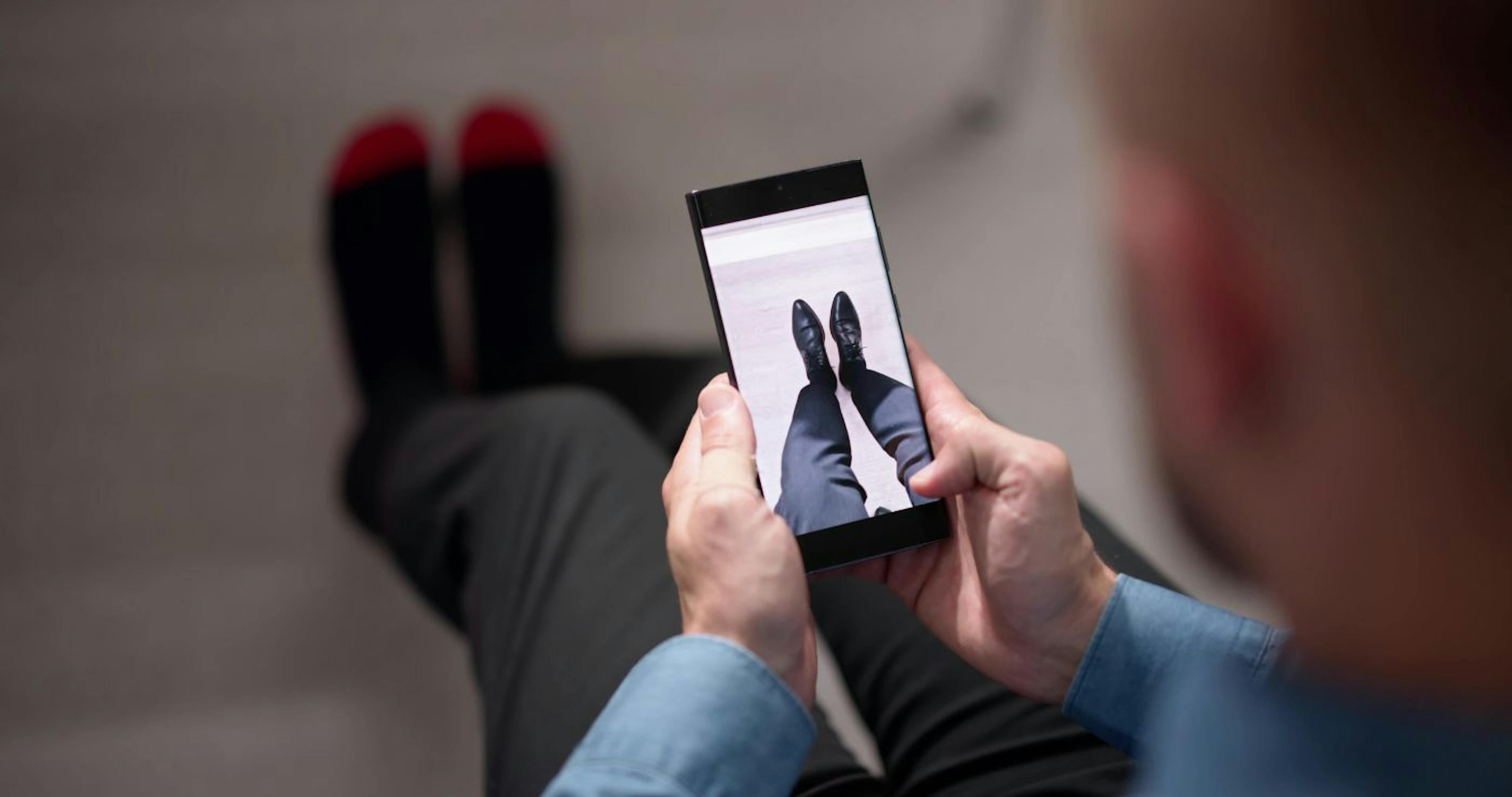 A customer virtually trying on a pair of shoes using his phone before making a purchase online.