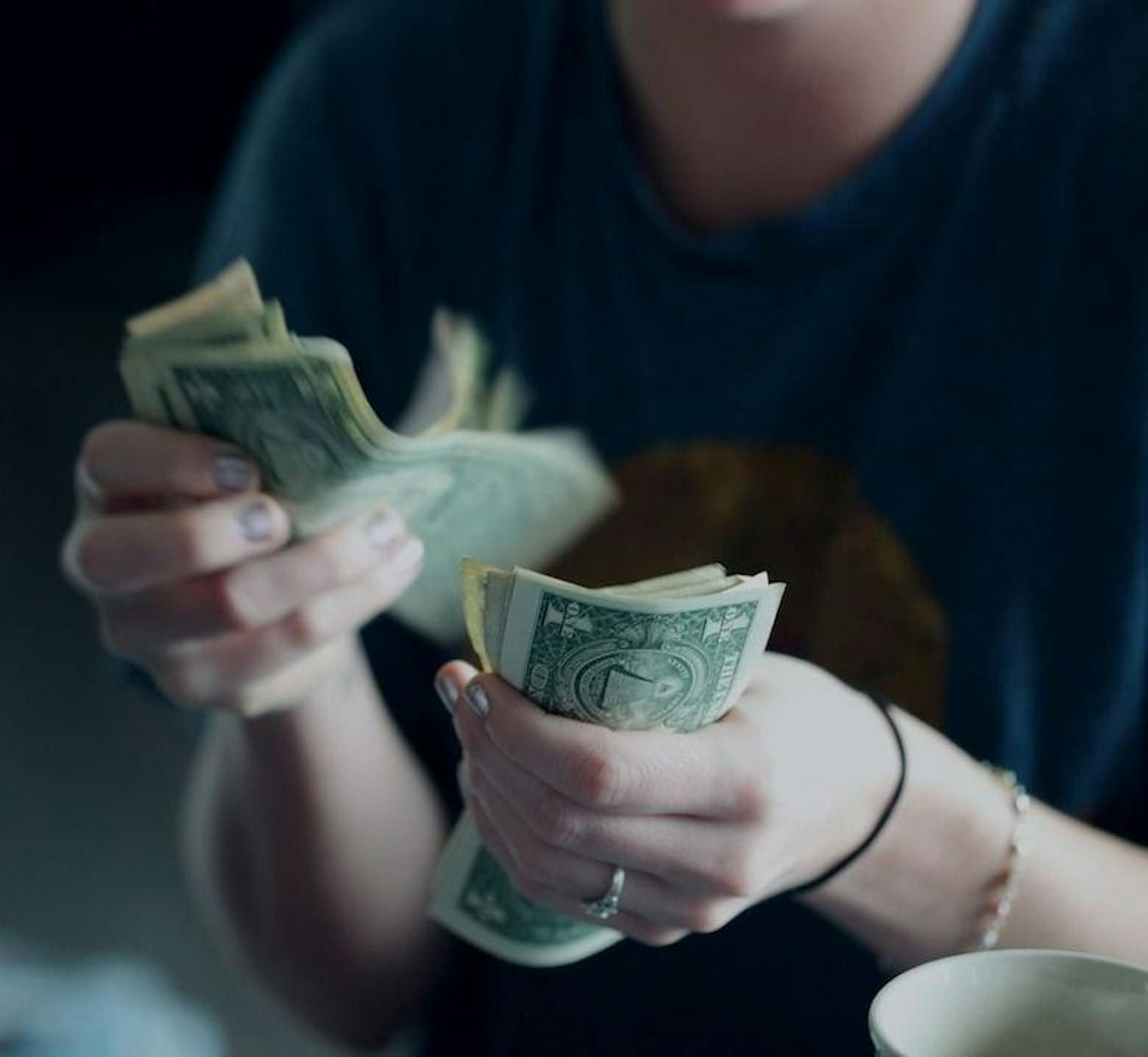 Una imagen de una persona con dinero en ambas manos como si estuviera contando