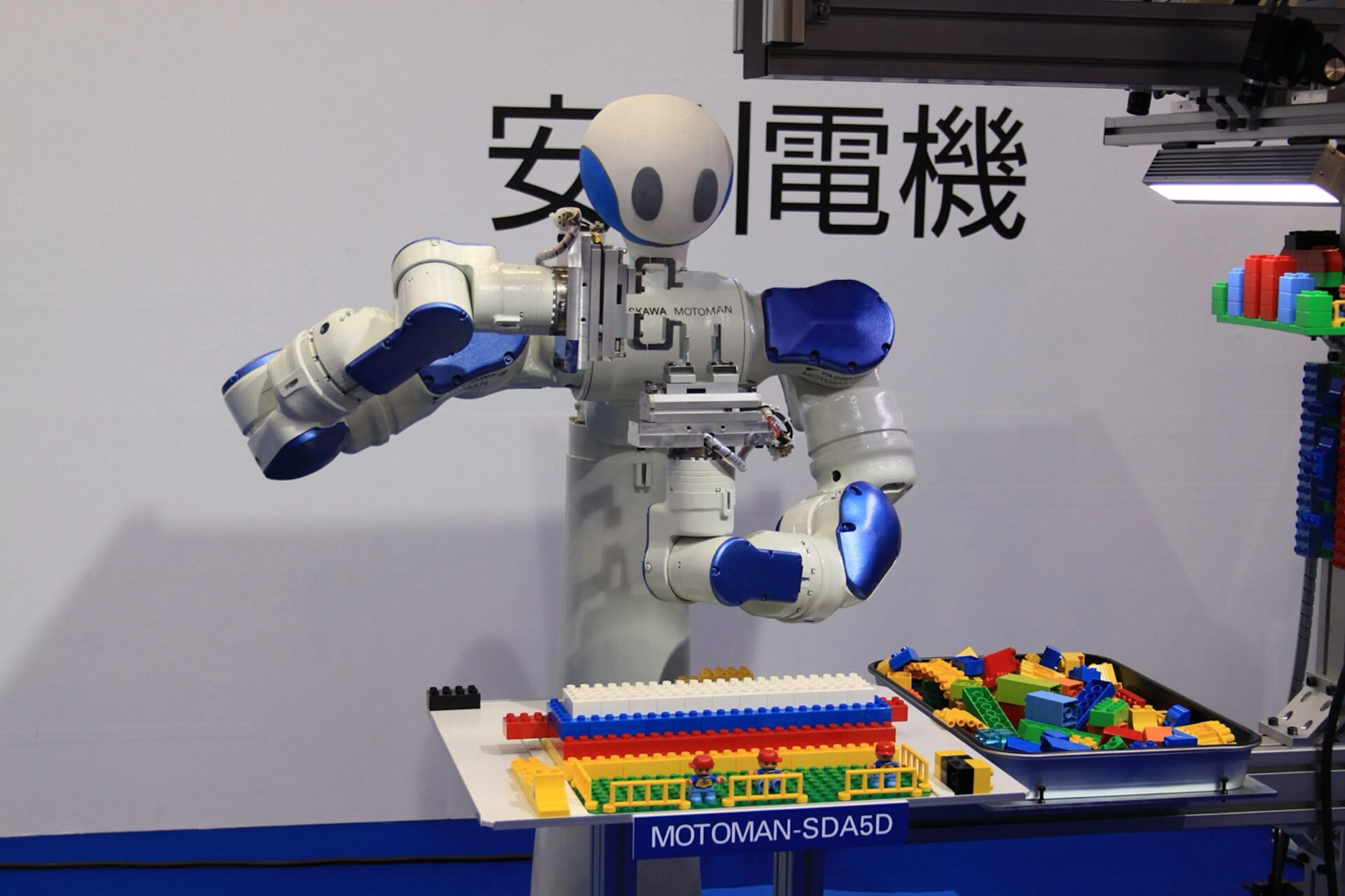 A Yaskawa Motoman dual-arm robot precisely assembling parts beneath the company's logo. Japan's bet is on dext