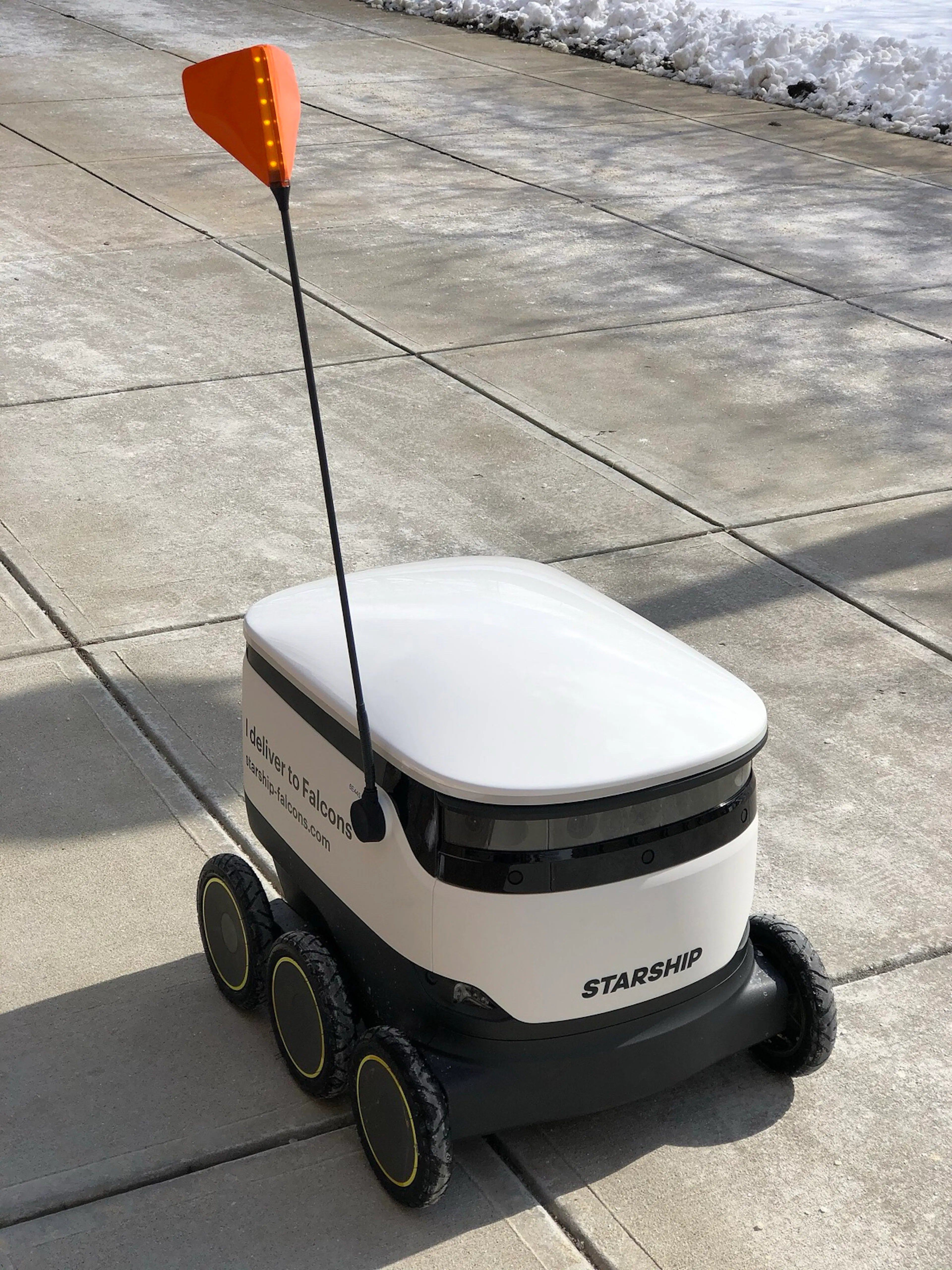 A six-wheeled Starship delivery robot navigating a sidewalk in winter. Boring by design, and wildly successful because of it.