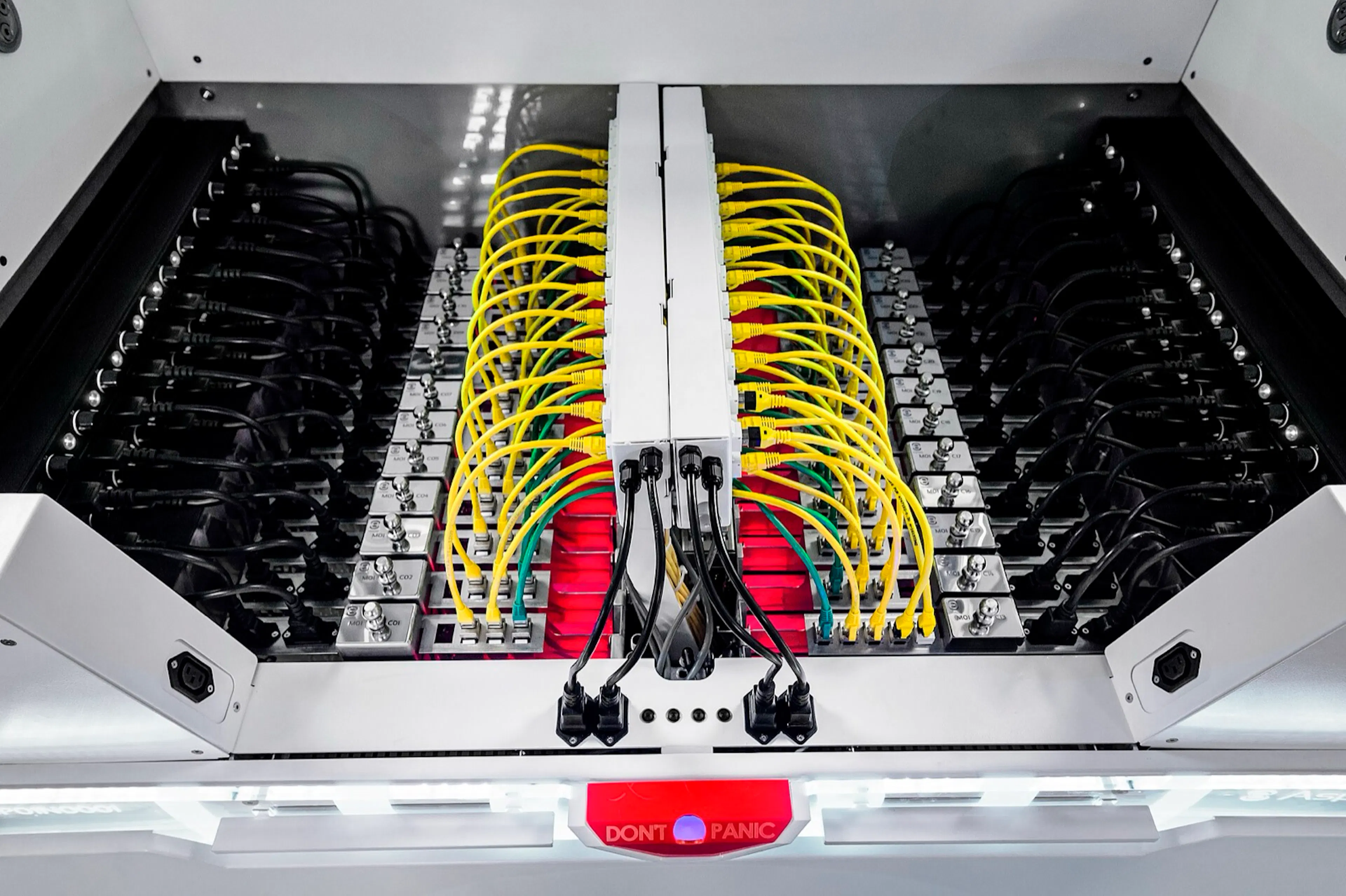 Looking down into an open immersion cooling tank, servers submerged in dielectric fluid with yellow network cables