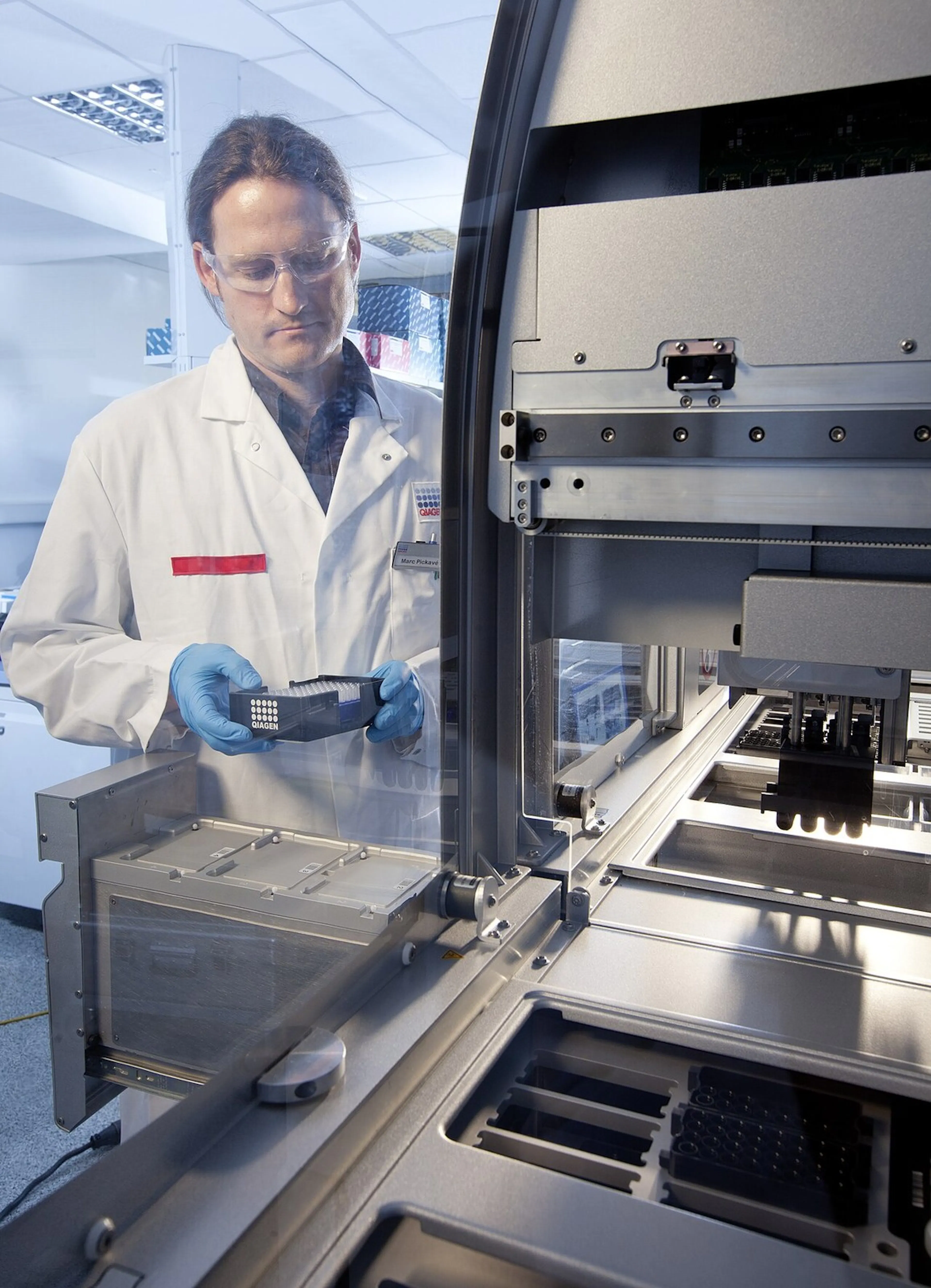 A researcher loading samples into an automated laboratory instrument