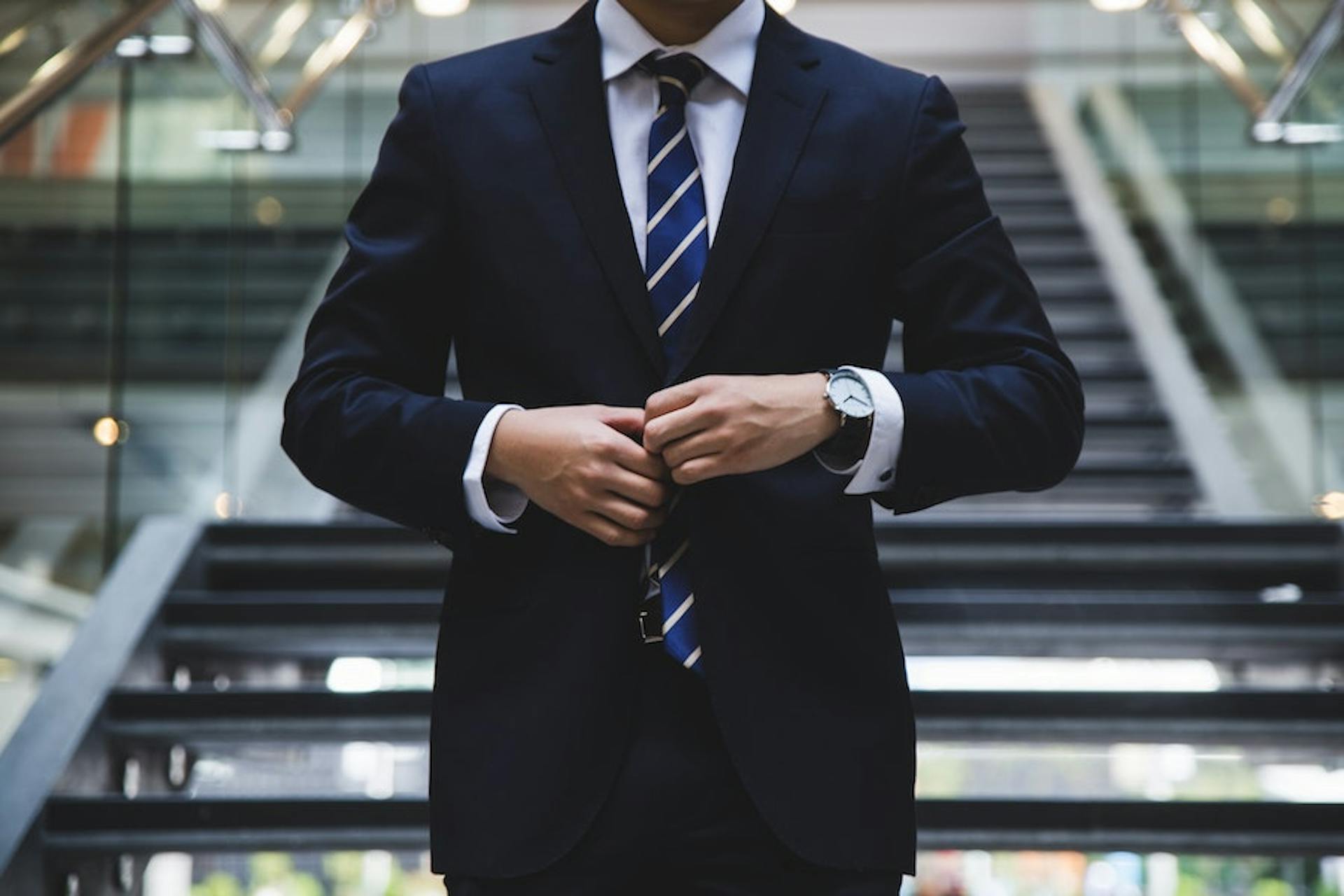 A man in a handsome suit descending stairs.