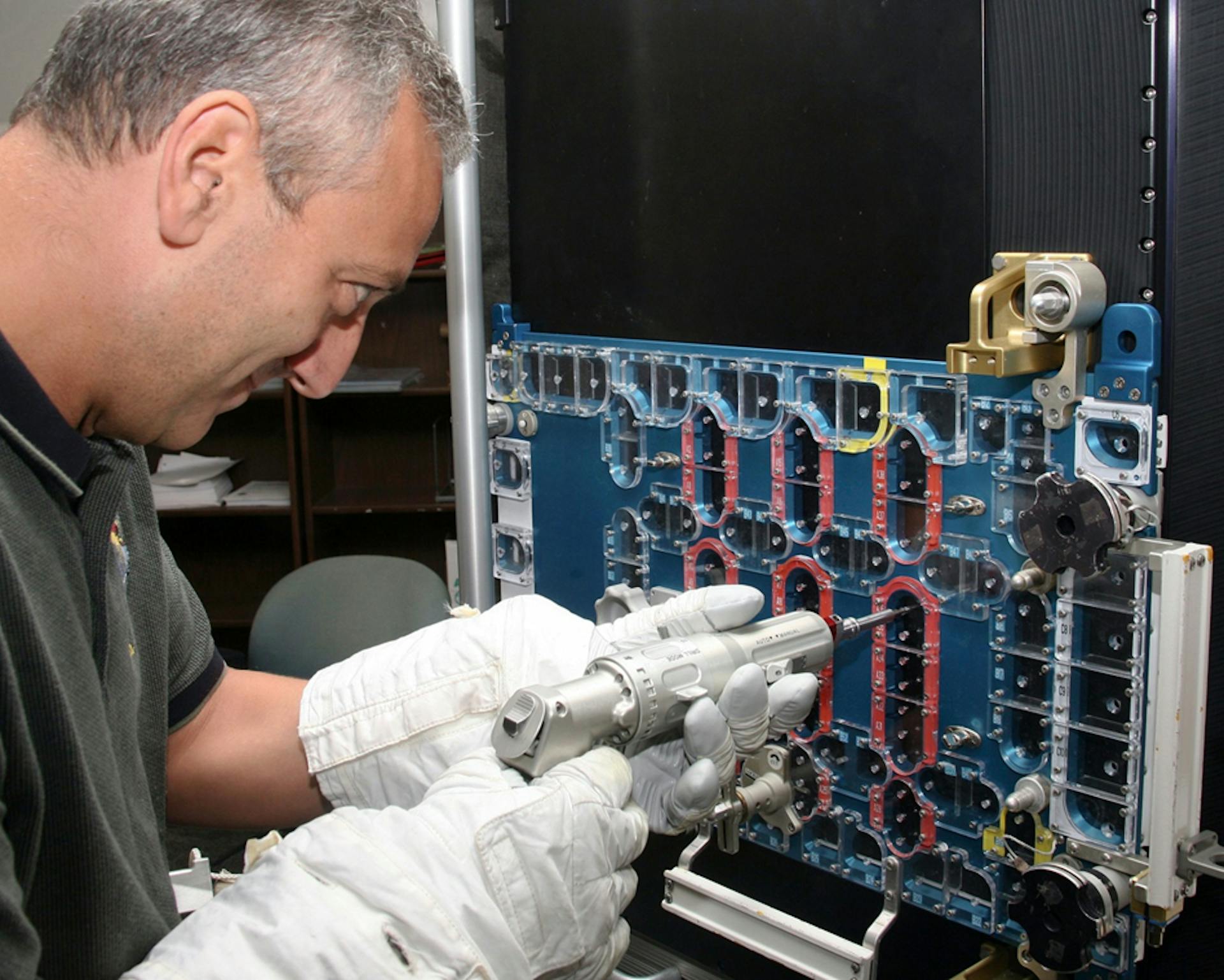 Astronaut Mike Massimino uses a version of the Mini Power Tool on the STIS model during preparations for the 4th servicing mission